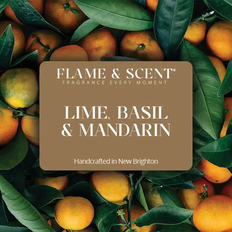 LBM Flame & Scent A brown label with white text reads FLAME & SCENT FRAGRANCE EVERY MOMENT Lemongrass & Ginger Candle Handcrafted in New Brighton, set over green lemongrass leavesโperfect for a refreshing citrus or spicy ginger aroma.