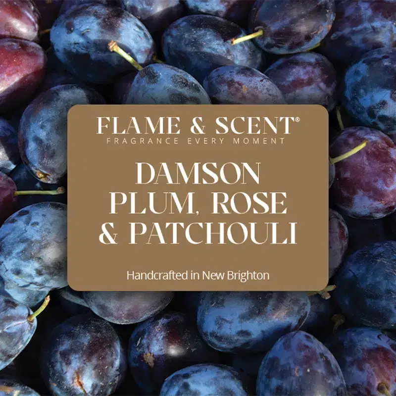 DPRP Flame & Scent A close-up of ripe damson plums with a label overlay reading Damson Plum, Rose & Patchouli Candle, Handcrafted in New Brighton.