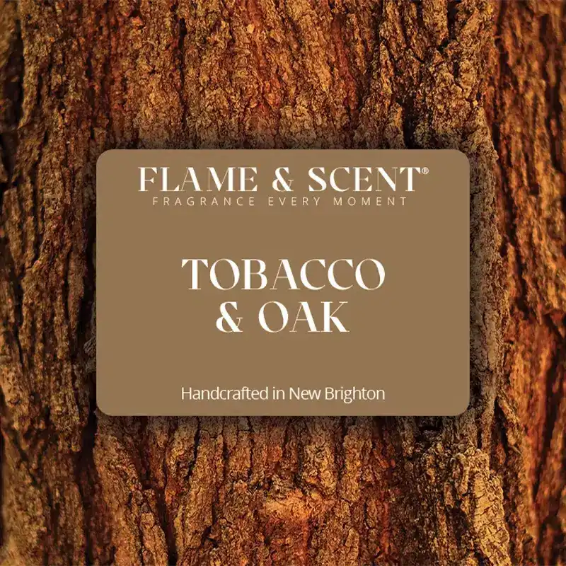 Flame & Scent A close-up of tree bark features a brown label reading FLAME & SCENT, Cedarwood & Jasmine Reed Diffuser, handcrafted in New Brighton with hints of jasmine and cedarwood.