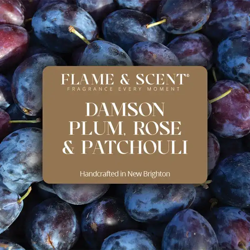 Flame & Scent A close-up of ripe damson plums with a label overlay reading Damson Plum, Rose & Patchouli Candle, Handcrafted in New Brighton.
