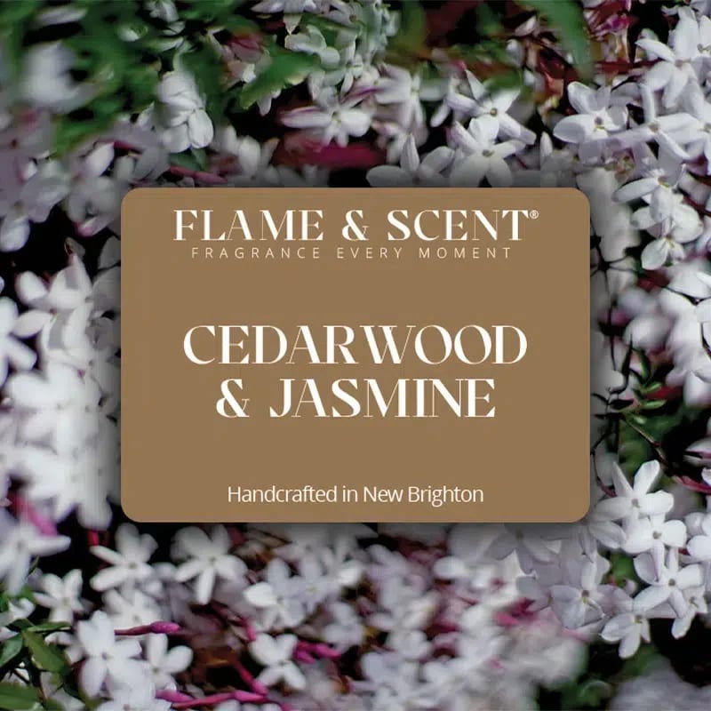 Flame & Scent A brown FLAME & SCENT label reading "Cedarwood & Jasmine Reed Diffuser" is centred against a background of white jasmine flowers and green leaves.
